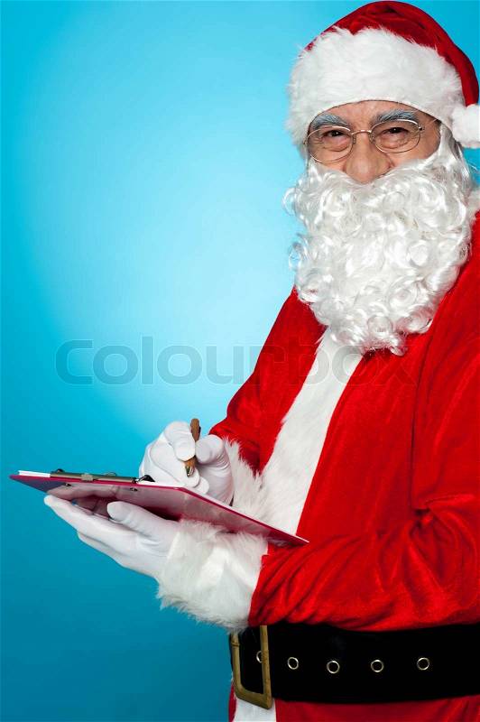 Santa Claus making notes in the wish list, stock photo