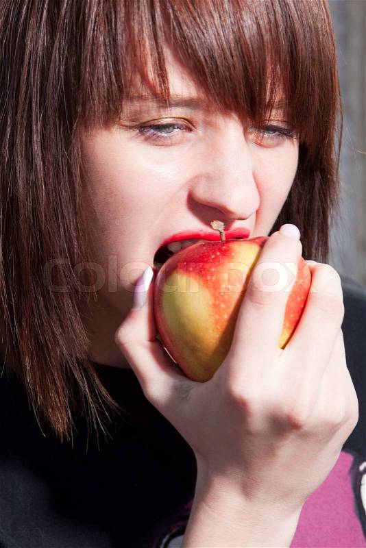 Young beautiful girl bites an red apple, stock photo