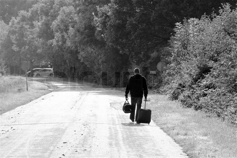 Sad story, the solitary man with suitcases is walking and he is leaving in black and white, stock photo
