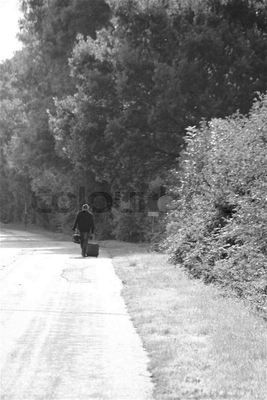 Sad story, the solitary man with suitcases is going and walk on the street with trees in black and white, stock photo