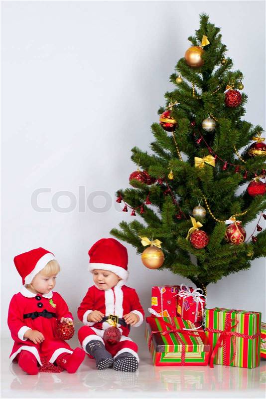 Two children sifting under christmas pine, stock photo