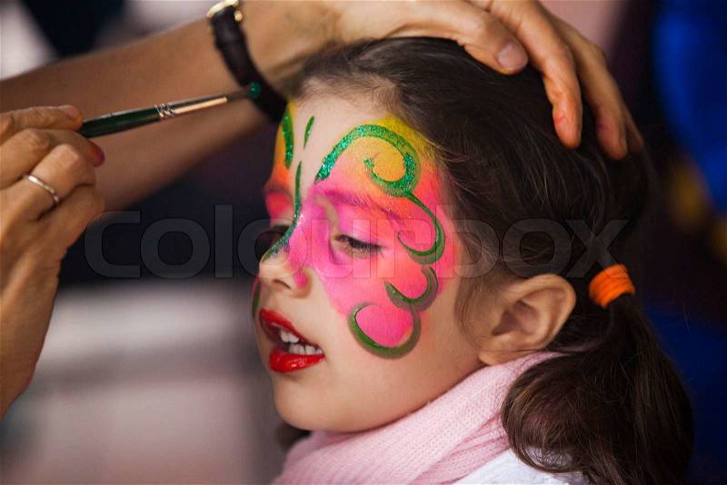 Little girl having face painted on party, stock photo