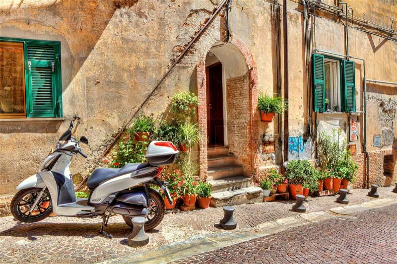 Motorcycle on narrow cobbled street in front of old house in town of Ventimiglia, Italy, stock photo