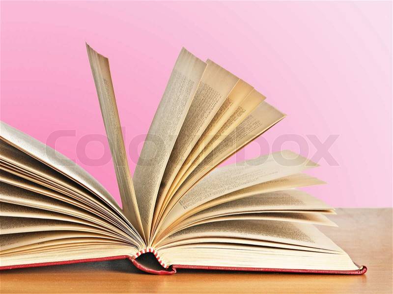 Open book on deskon pink background, stock photo