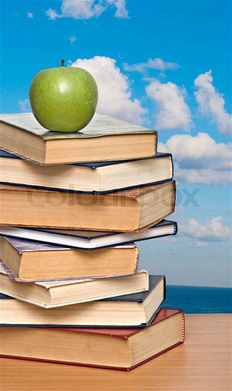 Green apple on pile of books, stock photo