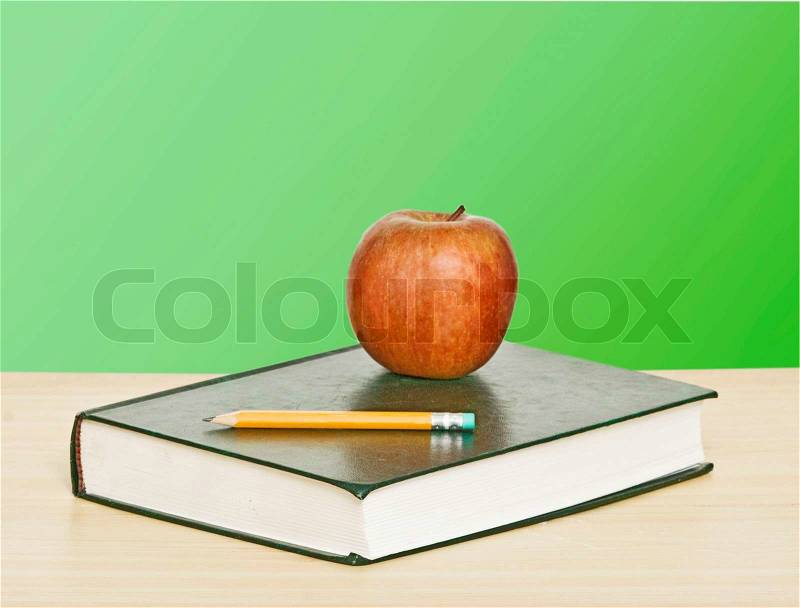 Red apple and pencil on top of book, stock photo