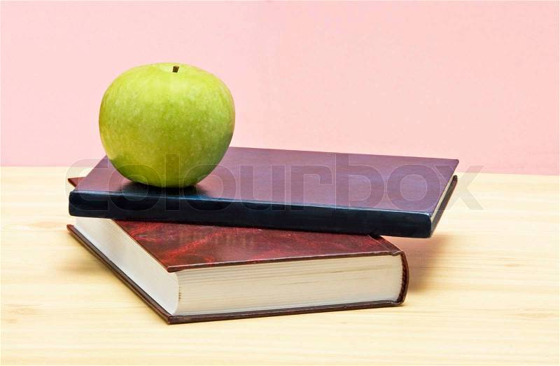 Green apple on books on desk, stock photo