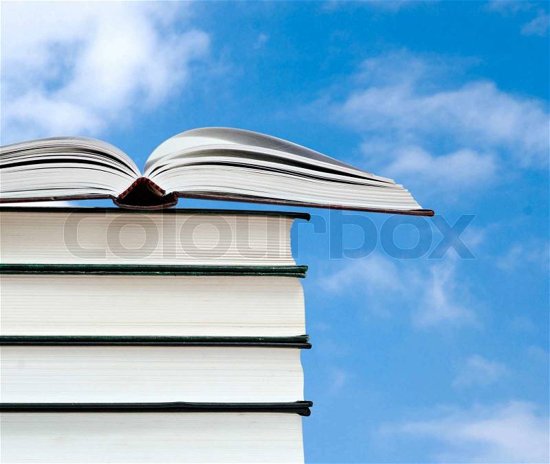 Open book and pile of books isolated on pink background, stock photo