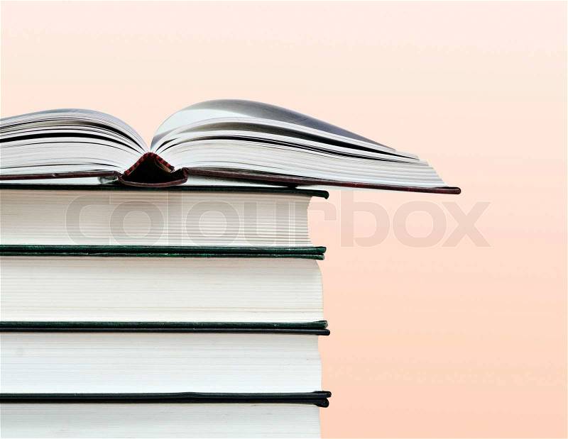 Open book and pile of books isolated on pink background, stock photo