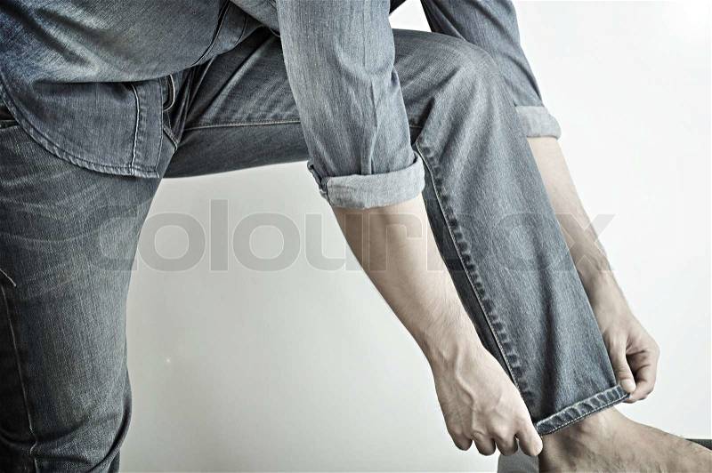 Man wearing jeans folding up pant leg, stock photo