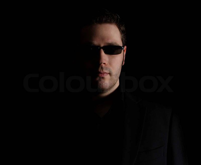 Portrait of man in black suit on black background, stock photo
