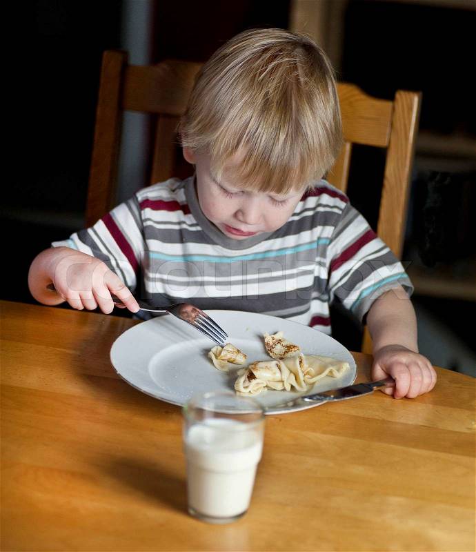 Young boy eating pancake, stock photo