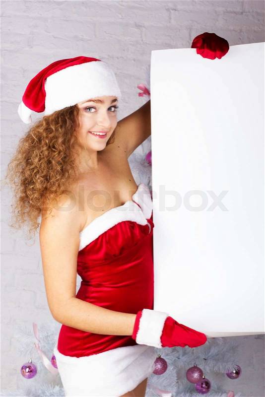Sexy young woman in Christmas clothes holding white board over Christmas background, stock photo