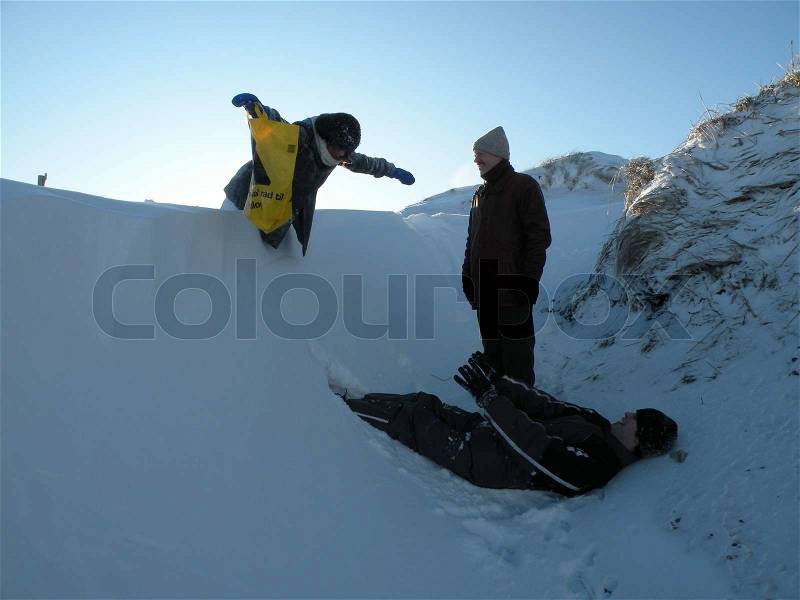 Person about to fall into deep snow on another person waiting to catch her, stock photo