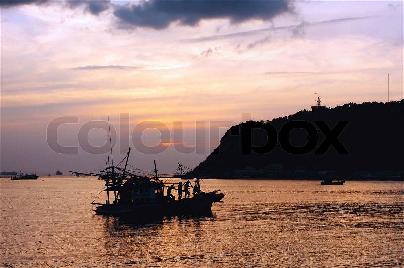 Silhouette of fisherman and boat in the bay during sunset, stock photo