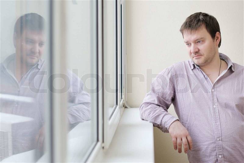Courageous middle age man looking at snow into the window, stock photo
