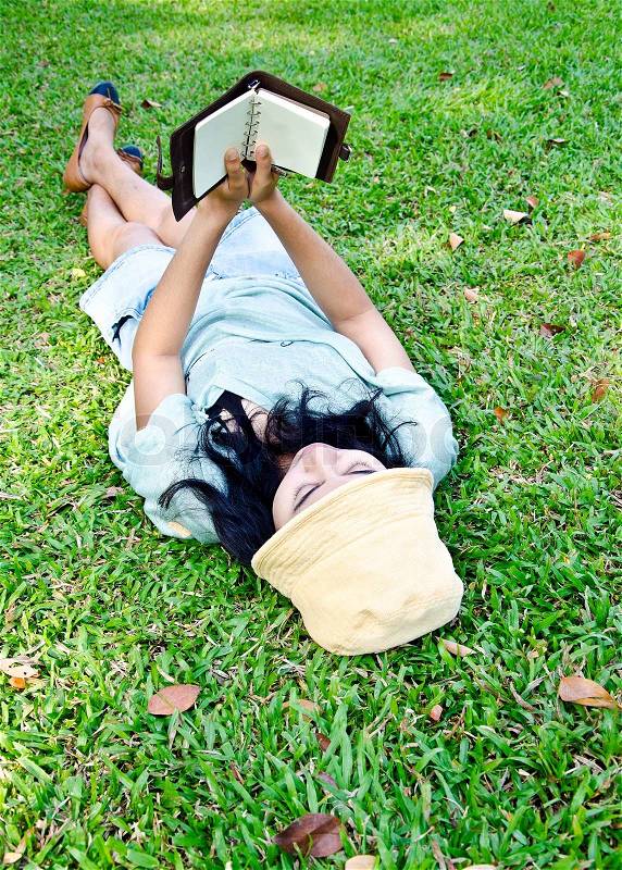Young woman reading a book in park, stock photo