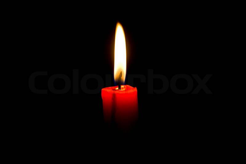 Closeup of burning red candle isolated on black background, stock photo