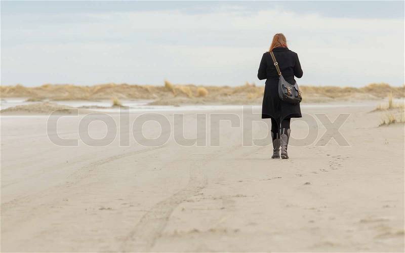 Lonely woman walking on a beach, stock photo