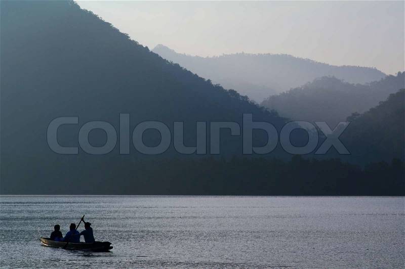 A boat is paddled towards over calm water They leave a small wake as their boat cuts through the water, stock photo
