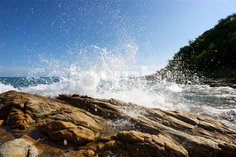 The waves breaking on a stony beach, forming a spray, stock photo