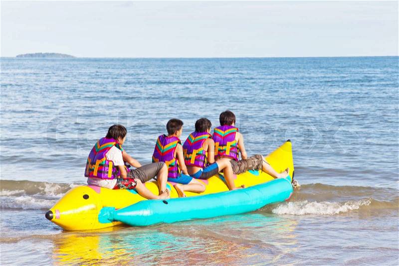 Group of young people riding banana boat, stock photo