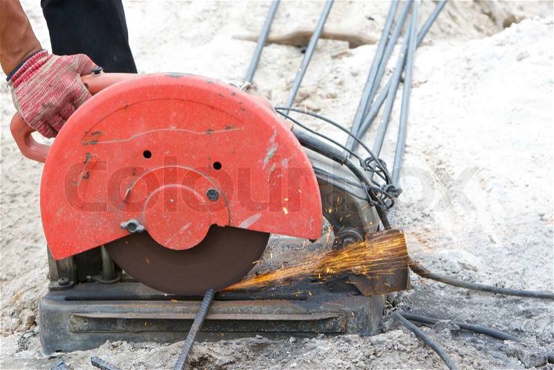 Builder worker cutting steel rod by machine on a day at the construction site, stock photo