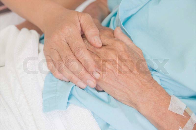 A young hand touches and holds an old wrinkled hand, stock photo