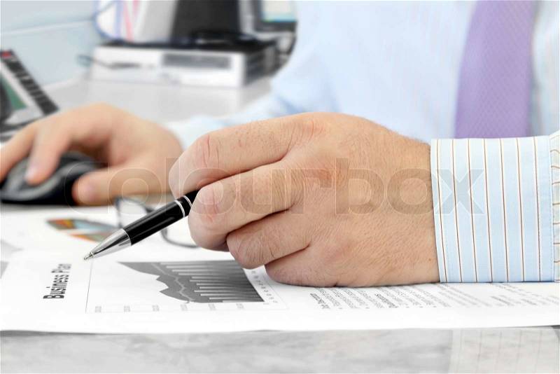 Male Hand with Pen Analyzing Financial Data in the Office, stock photo