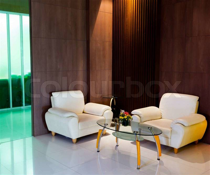 Modern interior decoration with white armchair and glass table in the corner of a room, stock photo