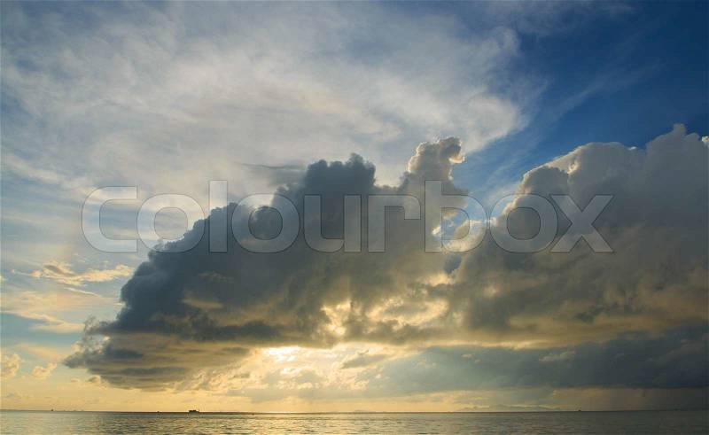 Big rain cloud over ocean at dusk, stock photo