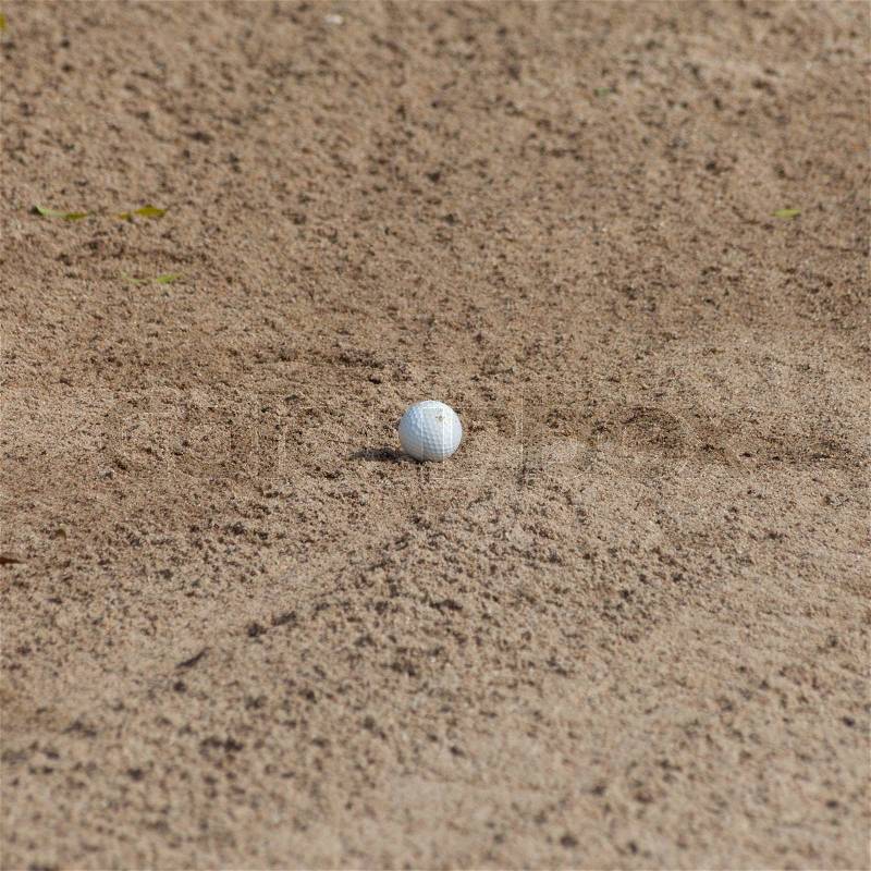 A golf ball in a sand trap, stock photo
