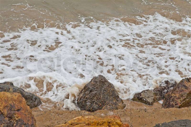 Water swirling around beach rocks, stock photo