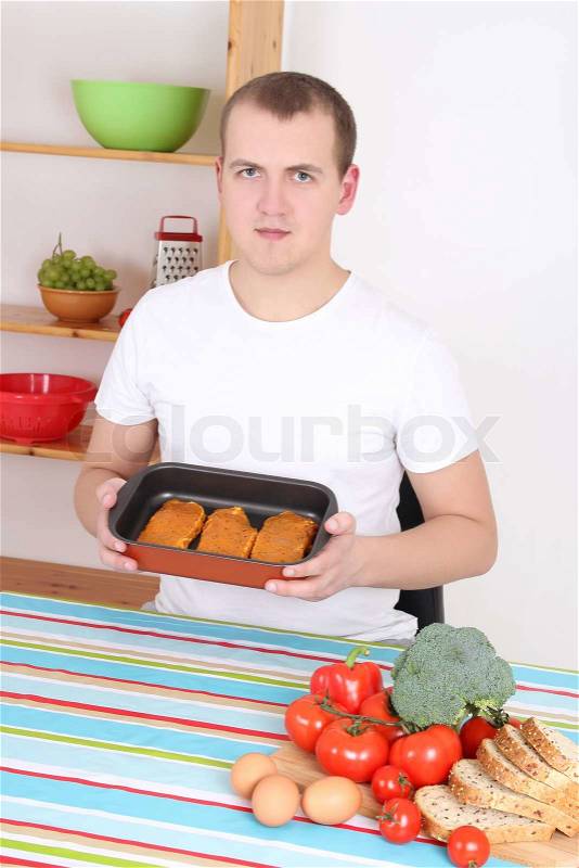 Young man cooking meat in the kitchen, stock photo