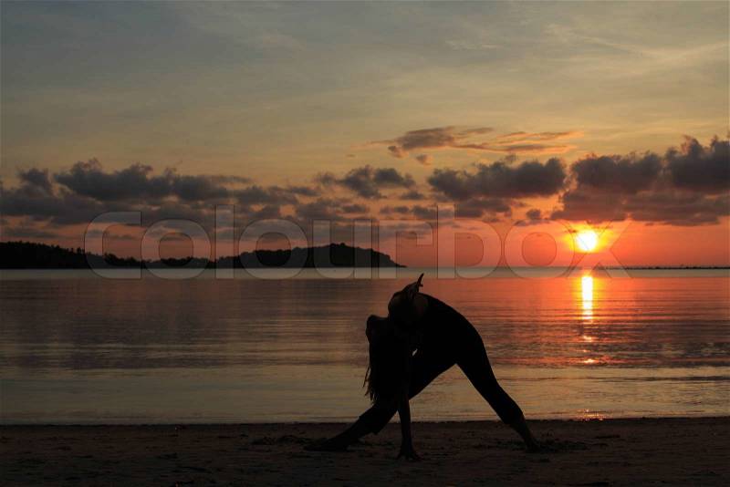 Silhouette of a beautiful yoga girl at sunrise on the beach,Extended Triangle Pose, stock photo