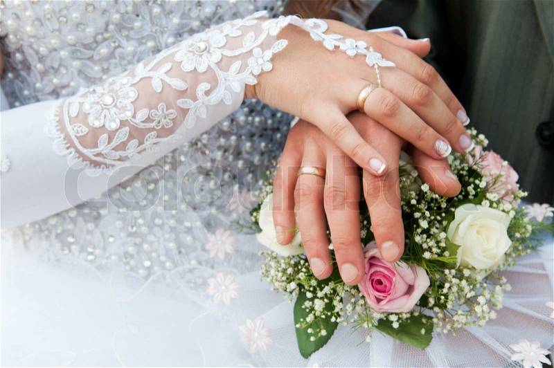Hands and rings on wedding bouquet, stock photo