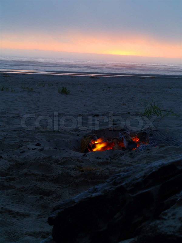 Beach Campfire at Dusk with Ocean in the background, stock photo