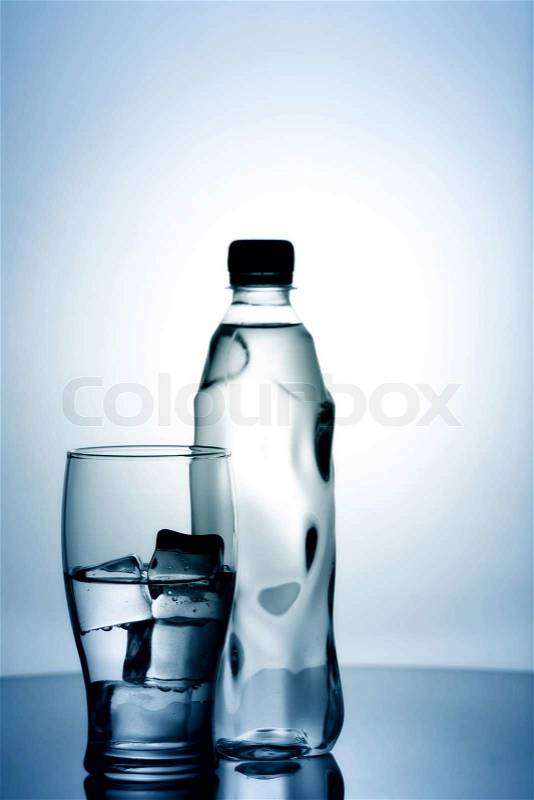 Glass of cold mineral water with ice and plastic bottle, stock photo