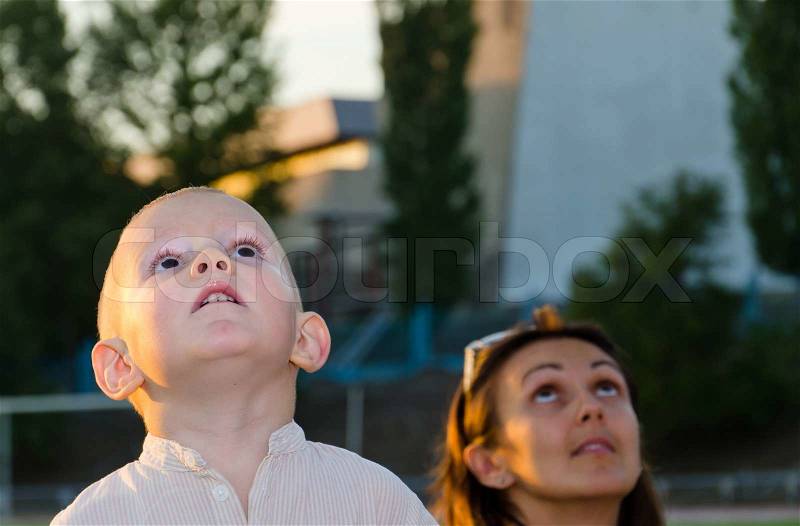 Young boy and his mother looking at the sky, stock photo