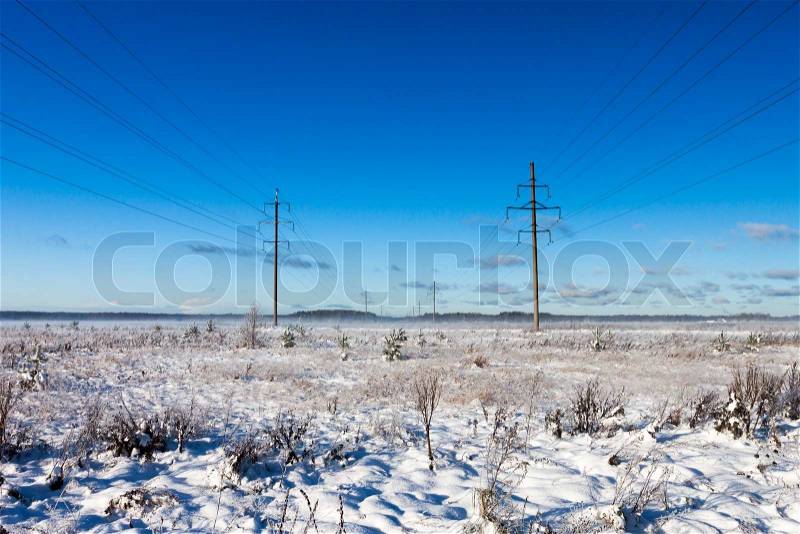 Power lines in winter snow field on a background of the blue sky, stock photo