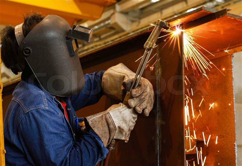 Worker using torch cutter to cut through metal, stock photo