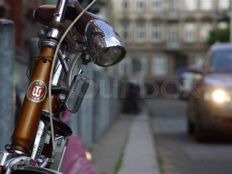 Cropped image of retro bicycle park on street with blurred car in background, stock photo