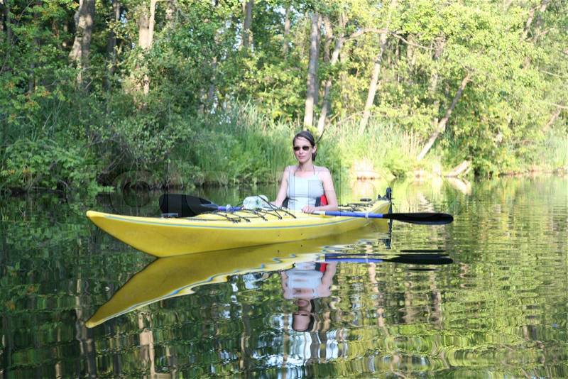 Young, brunette woman swimming in kayak in lake, stock photo