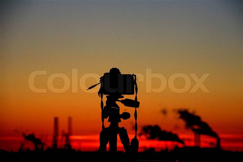 The camera in silhouette makes a picture from the industry with a beautiful sky at sunset, stock photo