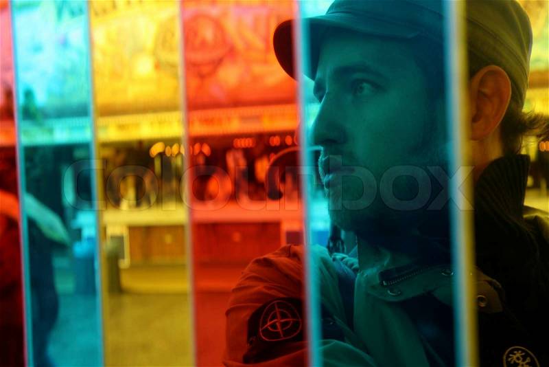 Face of young man from behind colourful glass, stock photo