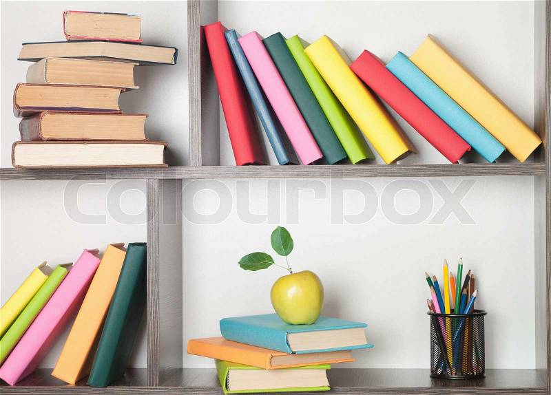 Colorful book, apple and pencils on the bookshelf , stock photo