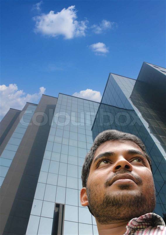 Handsome smart businessman/executive with modern building background looking forward confidently about future. The young adult is of Indian origin , stock photo