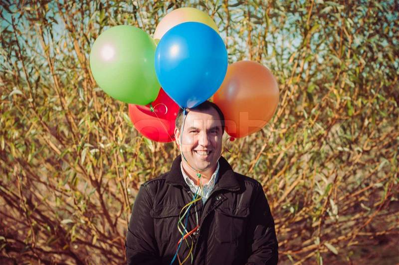 Young man with lot of balloons outdoor, stock photo