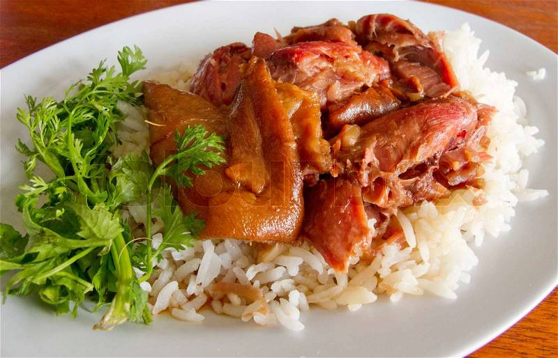 Thai stewed pork leg with rice and parsley Kao Ka Moo on white plate, stock photo