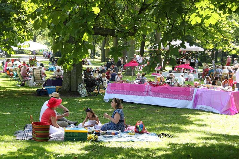 A sweet table with pink table cloth and many people have a picnic in this park, enjoy the summer, stock photo